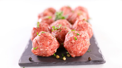 raw meatballs with parsley on white background