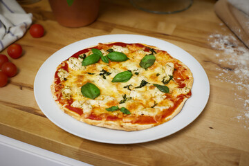 Homemade artisan pizza on white plate on wooden counter top