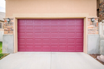 Burgundy closed garage door with two wall lamps on a brick wall