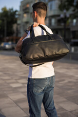 A man walks around the city holding bag on his shoulder