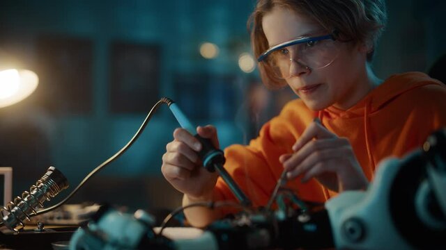 Smart Young Teenage Schoolboy is Studying Electronics and Soldering Wires and Circuit Boards in His Science Hobby Robotics Project. Kid is Working on a Robot in His Room. Education Concept.
