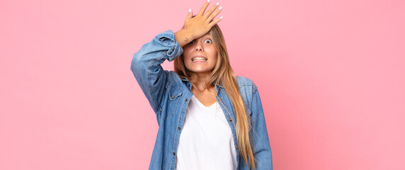 blonde pretty woman raising palm to forehead thinking oops, after making a stupid mistake or...