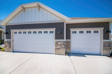 Home exterior with white double garage doors with windows and half stone walls