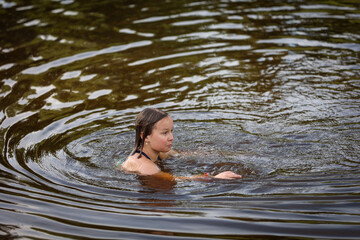 A girl swims in the river on a hot summer day