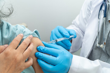 Doctors wear medical masks and vaccinated to senior women patients for the prevention of coronavirus and flu. Concept of immunization from inoculation