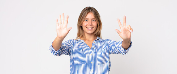 blonde pretty woman smiling and looking friendly, showing number nine or ninth with hand forward,...
