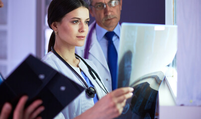 Group of doctors examining x-rays in a clinic, thinking of a diagnosis