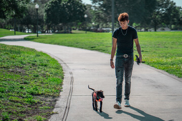 Latin man walks his puppy, dog at the park. Summer activities 