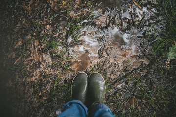 Woman's feet in rubber boots on a rainy day, space for your text.