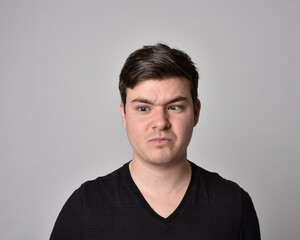 Obraz premium Close up head and shoulders portrait of a brunette. young man with a variety of expressive facial expressions. Isolated on a light grey studio background.