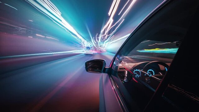 Beautiful motion timelapse of a speedy night drive in a big city, seamlessly looped. Side view from the car window to the road with neon light trails from vehicles and street lights. 