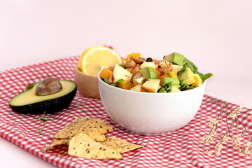 Bowl of mix fresh fruit salad on table color cloth pink background.