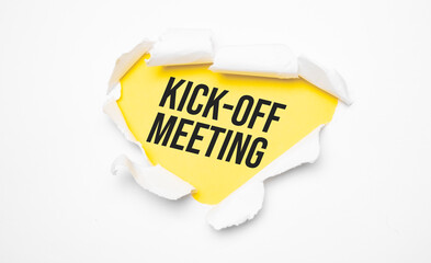Top view of white torn paper and the text KICK-OFF MEETING on a yellow background.