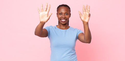 afro black adult woman smiling and looking friendly, showing number nine or ninth with hand...