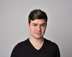 Close up head and shoulders portrait of a brunette. young man with a variety of expressive facial expressions. Isolated on a light grey studio background.
