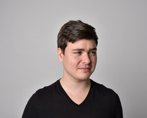 Fototapeta premium Close up head and shoulders portrait of a brunette. young man with a variety of expressive facial expressions. Isolated on a light grey studio background.