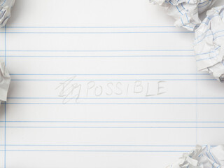 Notebook with the word "possible" written on it and several balls of crumpled paper.