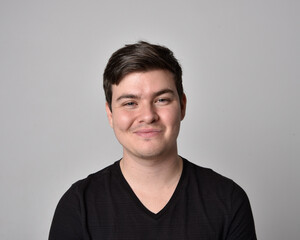 Fototapeta premium Close up head and shoulders portrait of a brunette. young man with a variety of expressive facial expressions. Isolated on a light grey studio background.