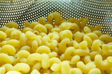 Yellow spiral pasta in an aluminum colander
