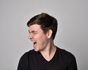 Fototapeta premium Close up head and shoulders portrait of a brunette. young man with a variety of expressive facial expressions. Isolated on a light grey studio background.