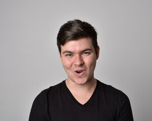 Fototapeta premium Close up head and shoulders portrait of a brunette. young man with a variety of expressive facial expressions. Isolated on a light grey studio background.