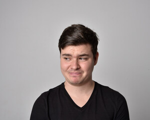 Obraz premium Close up head and shoulders portrait of a brunette. young man with a variety of expressive facial expressions. Isolated on a light grey studio background.