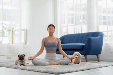 Fotobehang Beautiful Asian woman practice yoga lotus pose with dog pug breed and poodle relax with yoga at home,Recreation Exercise with Dog ,Wellness woman breathing and meditation with yoga and dog small pet © 220 Selfmade studio