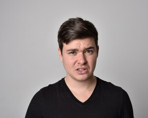 Obraz premium Close up head and shoulders portrait of a brunette. young man with a variety of expressive facial expressions. Isolated on a light grey studio background.