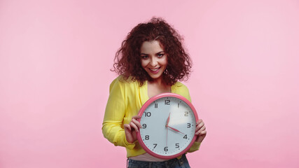 happy young woman holding clock isolated on pink