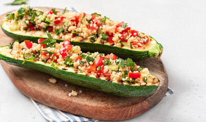 Grilled zucchini stuffed with couscous, tomatoes, cucumber and parsley. Vegan stuffed zucchini on a...