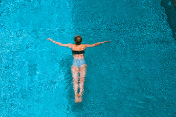 A beautiful girl is swimming in the pool. Relax at the hotel by the pool. Summer holidays. 