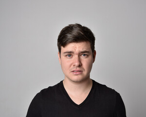 Obraz premium Close up head and shoulders portrait of a brunette. young man with a variety of expressive facial expressions. Isolated on a light grey studio background.