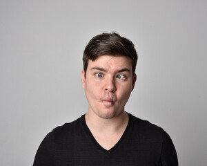 Obraz premium Close up head and shoulders portrait of a brunette. young man with a variety of expressive facial expressions. Isolated on a light grey studio background.