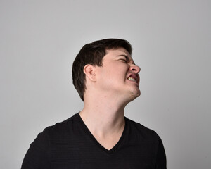Close up head and shoulders portrait of a brunette. young man with a variety of expressive facial expressions. Isolated on a light grey studio background.