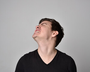 Close up head and shoulders portrait of a brunette. young man with a variety of expressive facial expressions. Isolated on a light grey studio background.