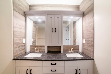 Alcove double vanity sink with wood panel walls and cabinet