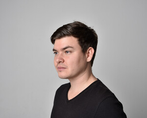 Close up head and shoulders portrait of a brunette. young man with a variety of expressive facial expressions. Isolated on a light grey studio background.