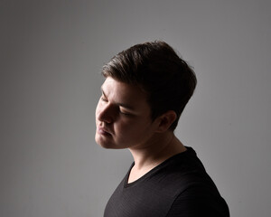 Fototapeta premium Close up head and shoulders portrait of a brunette. young man with a variety of expressive facial expressions. Isolated on a light grey studio background.