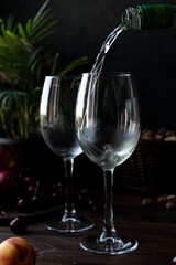 White wine is poured into glasses. There are fruits nearby
