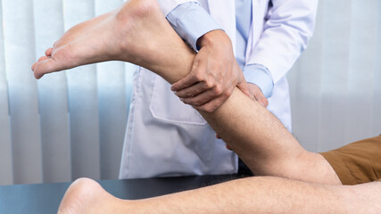Medical concept a male doctor diagnosing a male patient's leg by pressing his leg because of playing football