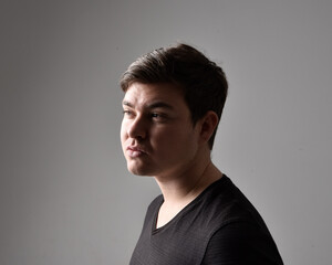 Close up head and shoulders portrait of a brunette. young man with a variety of expressive facial expressions. Isolated on a light grey studio background.