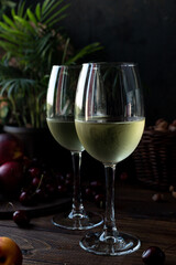 White wine is poured into glasses. There are fruits nearby