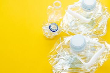 Used plastic bottles crushed and crumpled against on the yellow background. Recycling concept