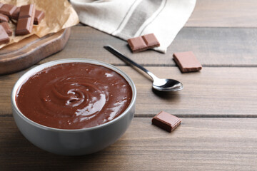 Delicious chocolate cream in bowl on wooden table, space for text