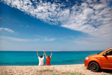 a couple are sitting at the seaside with clouds and car on background
