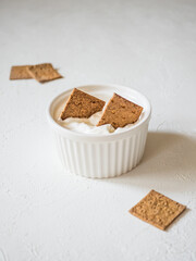 Flat natural mini crunchy bread in a gravy boat with sour cream. Dip the crunchy breads in the sauce. Delicious and natural dietary snacks.