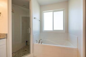 Naklejka na ściany i meble Interior of a bathroom with drop in bathtub and corner shower stall