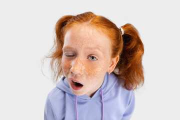 Close-up funny girl with freckled face and red hair looking at camera isolated on white studio...