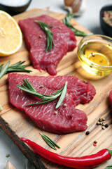 Fresh raw meat steaks and spices on wooden board, closeup