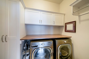 Laundry room with stainless laundry machines below the wooden desk